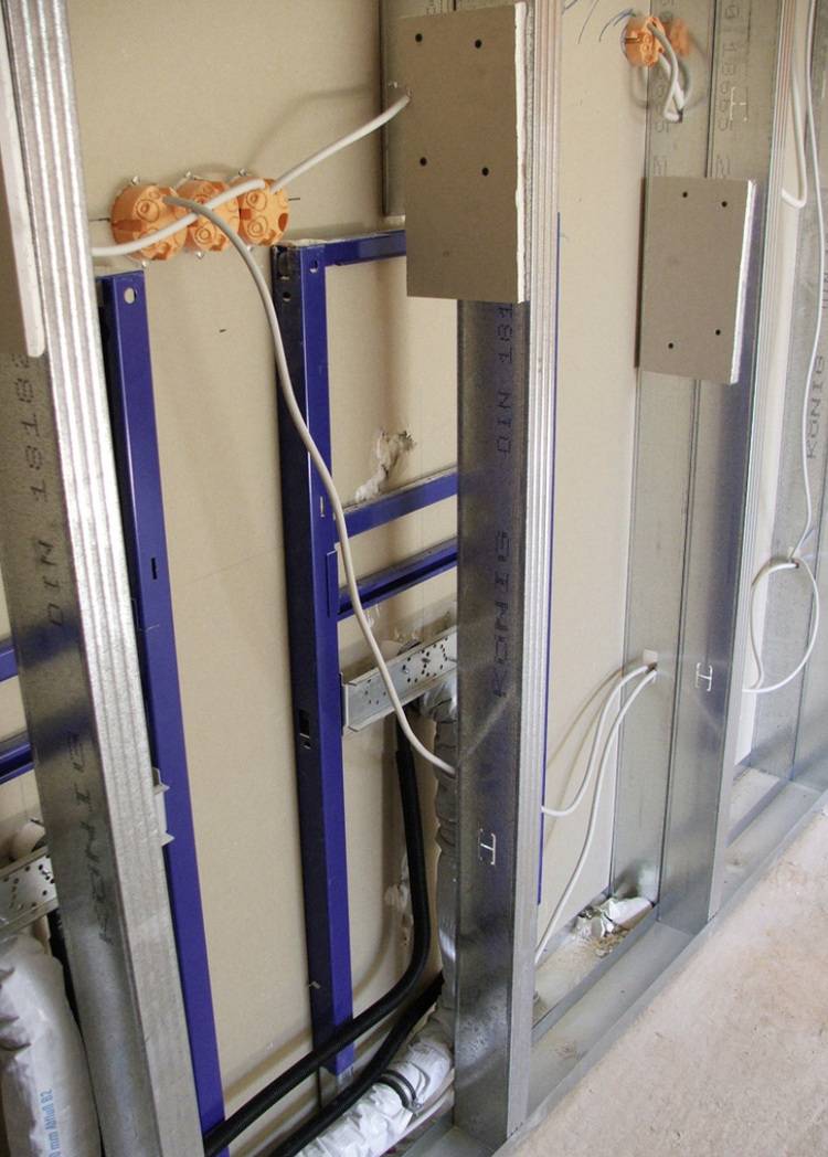 Alt-Text: „Installation von Metallständerwänden mit integrierter Elektroverkabelung und Steckdosen in einem Gebäude, um energieeffiziente und barrierefreie Zugangswege für die Gebäudetechnik zu gewährleisten.“.