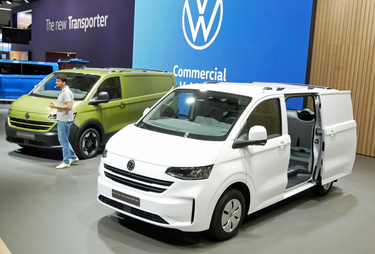 ALT-Text: „Zwei Volkswagen Nutzfahrzeuge: ein grüner und ein weißer Van, ausgestellt in einem Showroom, geeignet für den Einsatz im SHK-Bereich sowie in der Energieeffizienzberatung.