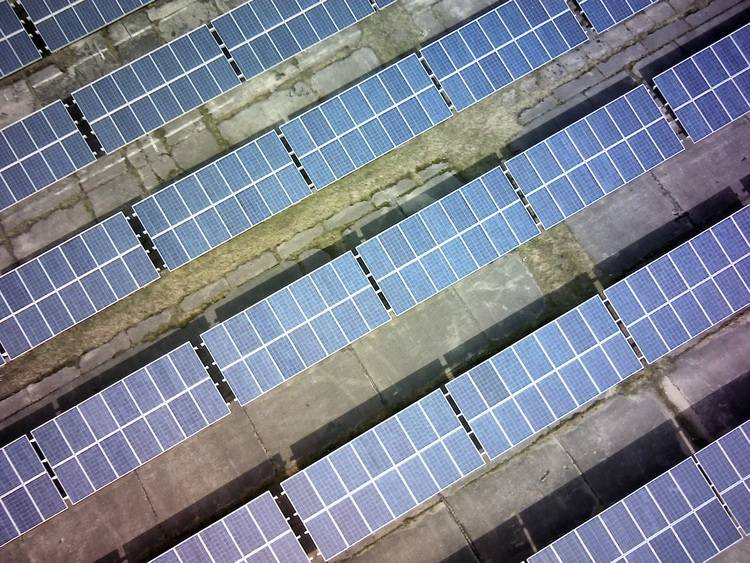 „Luftaufnahme von Solarmodulen auf einem Flachdach einer Gewerbeimmobilie, die effiziente Nutzung erneuerbarer Energien zur Reduzierung des CO2-Fußabdrucks und zur Optimierung der Energieeffizienz demonstriert.“.