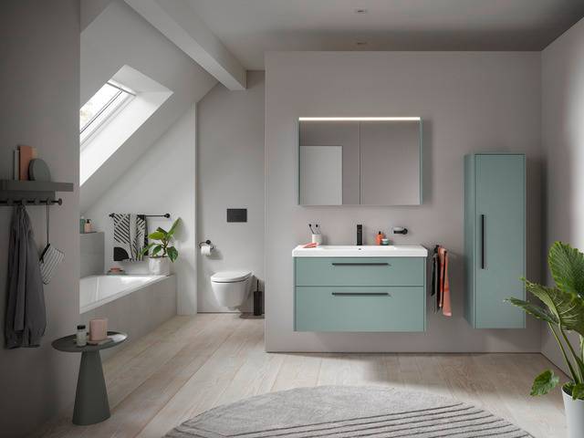 Alt-Text: „Modernes Badezimmer mit Oberlicht, ausgestattet mit mintgrünen Schränken, freistehender Badewanne und Holzfußboden; ideal für energieeffiziente Gebäudetechnik und ästhetisches Design in SHK-Anwendungen.