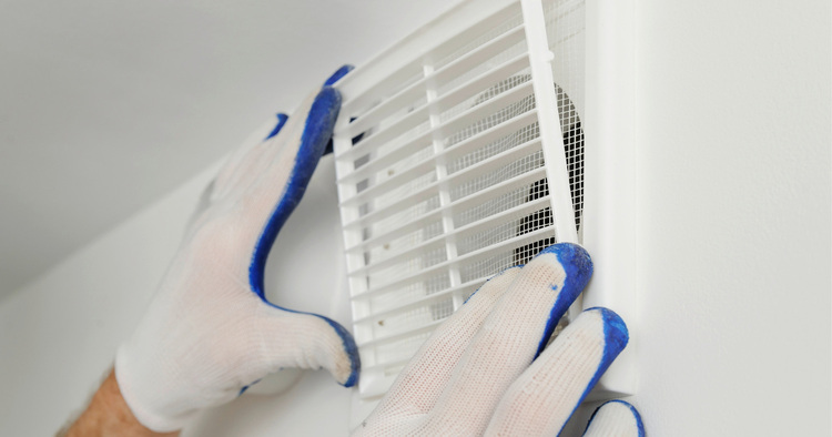 Barrierefreies Installationsverfahren: Fachhandwerker mit Schutzhandschuhen montiert effiziente, energieoptimierte Lüftungsabdeckung zur Verbesserung der Raumluftqualität in modernen Gebäudekonzepten.