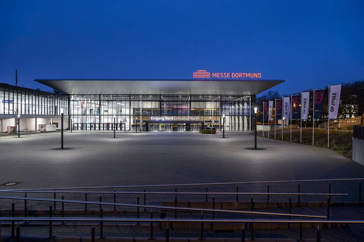 Alt-Text: „Nachtansicht des Messe Dortmund Ausstellungszentrums, beleuchtet für die ISH-Fachmesse, einem zentralen Branchenereignis für die neuesten Trends in Heizungstechnik und energieeffizienter Gebäudetechnik.