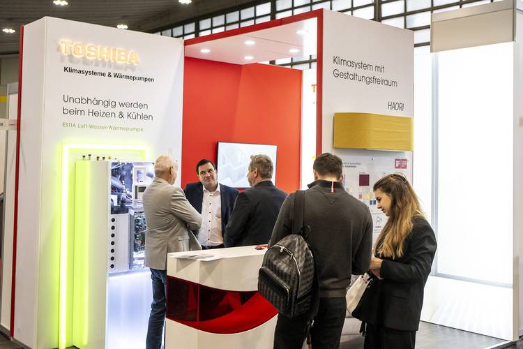 Toshiba-Messestand mit Fachleuten beim Besprechen von innovativen Heiz-, Lüftungs- und Klimasystemen während einer Fachmesse für Gebäudetechnik.