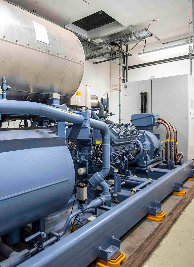 ALT-Text: Industrielle Heizungsanlage mit blauen Rohrleitungen und großem Wärmetank in einem Raum zur Energieeffizienzsteigerung, wichtig für TGA-Planer und SHK-Betriebe.