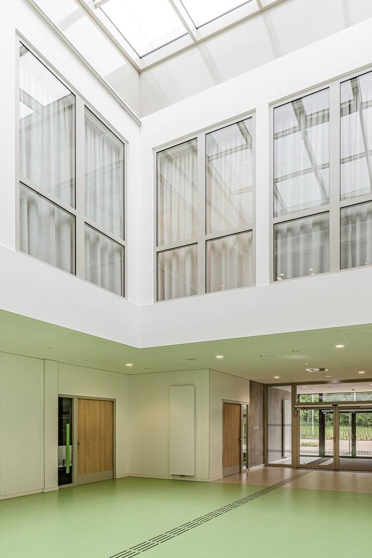 Alt-Text: „Moderne Büroetage in einem energieeffizienten Gebäude mit großen Fenstern für optimale Tageslichtnutzung, nachhaltigem Bodenbelag und hochwertigen Holztüren, betont die Bedeutung von Energieeffizienz und natürlicher Beleuchtung in der Gebäudetechnik.“.