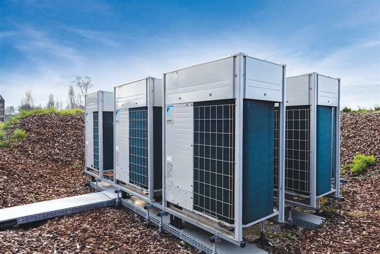 Alt-Text: „Moderne Außeneinheiten einer Klimaanlage auf einem Gebäudedach, strategisch positioniert für optimale Energieeffizienz, umgeben von Vegetationsinseln zur Verbesserung der CO2-Bilanz.