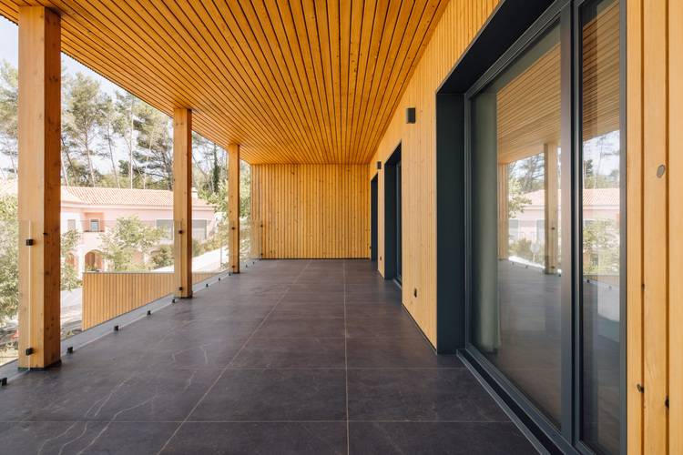 Alt-Text: „Großzügige Holzterrasse mit energieeffizienten, bodentiefen Glasschiebetüren, umgeben von einer nachhaltigen Landschaftsgestaltung – ideal zur Darstellung moderner Lösungen in der Gebäudetechnik für Architekten und Facility Manager.“.