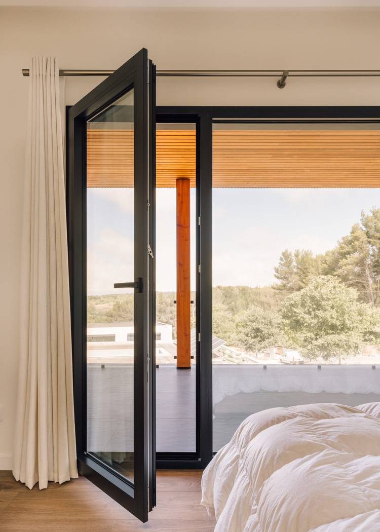 Alt-Text: „Moderne energiesparende Glas-Schiebetür mit isolierender Gebäudehülle, öffnet sich zu einem Balkon, Konzept für nachhaltiges Bauen in der Gebäudetechnik.