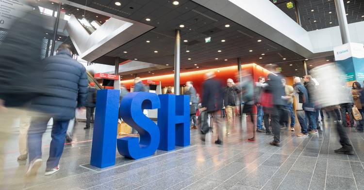 Alt-Text: „Teilnehmer der ISH-Fachmesse, Europas führender Veranstaltung für Sanitär-, Heizungs- und Klimatechnik, in einem belebten Messebereich mit großen blauen ‚ISH‘-Buchstaben im Hintergrund.