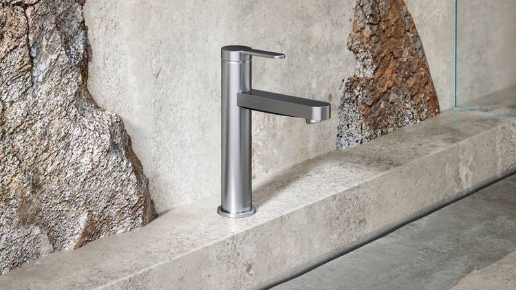 Silberne Armatur mit energieeffizienter Technologie auf einer strukturierten Steinoberfläche, geeignet für nachhaltige Gebäudekonzepte in der Sanitärtechnik.