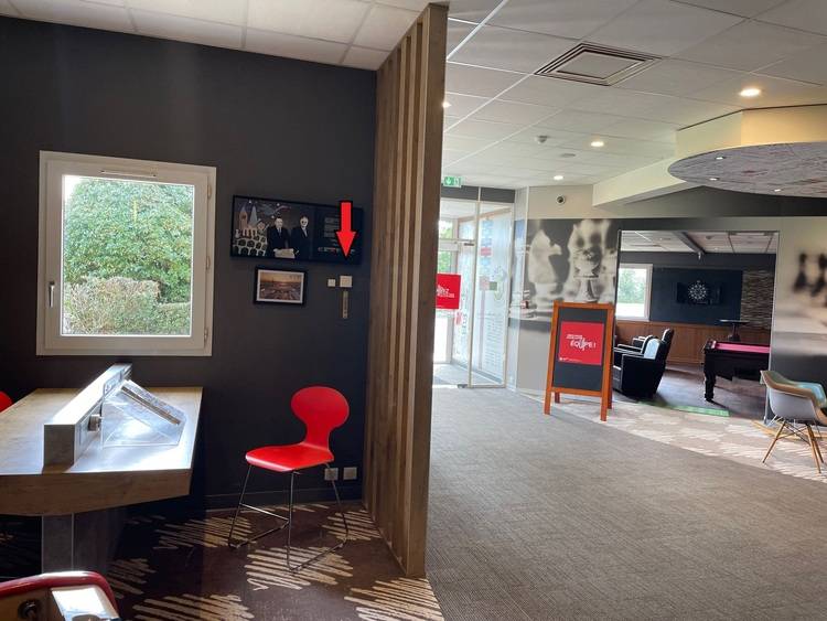 ALT-Text: „Moderne Lobby in einem energieeffizienten Gebäude mit stilvollem roten Stuhl als Wartebereich, kunstvoll gestalteter Wanddekoration und Glastüren mit optimierter Wärmedämmung für Nachhaltigkeit.