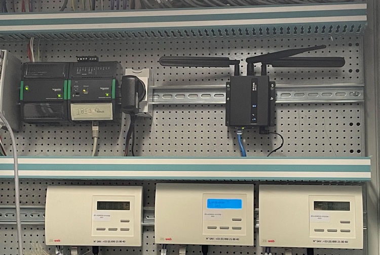 „Detailansicht eines elektrischen Schaltschrankes mit verschiedenen Steuergeräten, Routern und Zählern auf einer perforierten Montageplatte, symbolisiert die Verknüpfung von Gebäudeautomationssystemen für Effizienz und Zuverlässigkeit in der modernen Haustechnik.“.