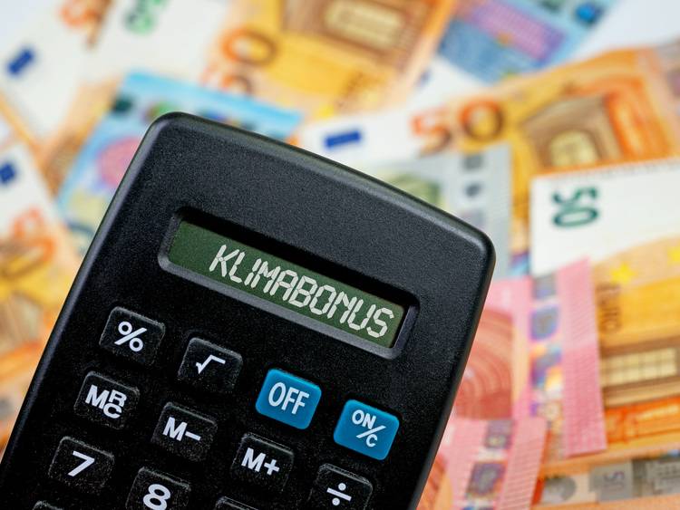 Ein Taschenrechner mit der Anzeige 'Klimabonus' vor einem Hintergrund aus Euro-Banknoten, symbolisiert finanzielle Anreize für energieeffiziente Investitionen im Bereich Gebäudetechnik.