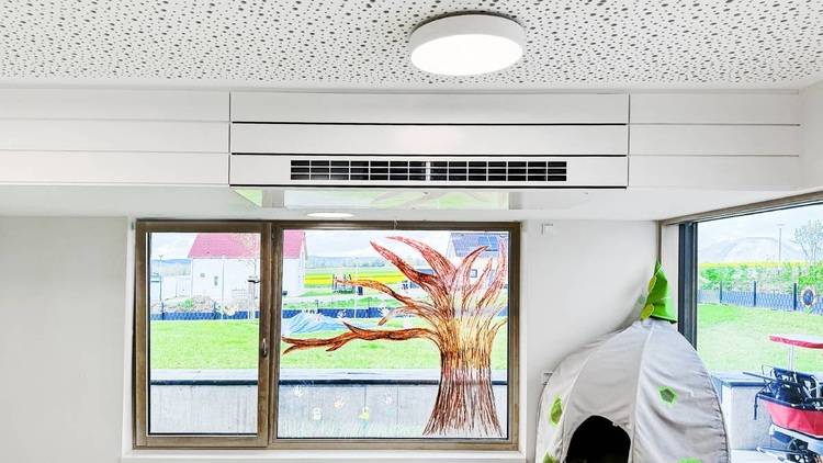 ALT-Text: „Moderner Technikraum mit energieeffizientem Lüftungssystem, große Fensterfront zur Maximierung des natürlichen Lichts und ein dekoratives Baum-Motiv zur Raumgestaltung.