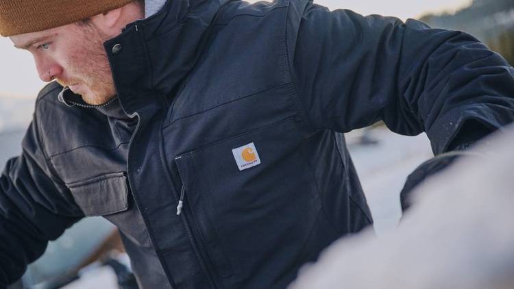 ALT-Text: „Ingenieur im Wintermantel inspiziert ein modernisiertes Energiesystem im Freien, um Energieeffizienz und nachhaltige Lösungen für gewerblich genutzte Gebäude zu bewerten.“.