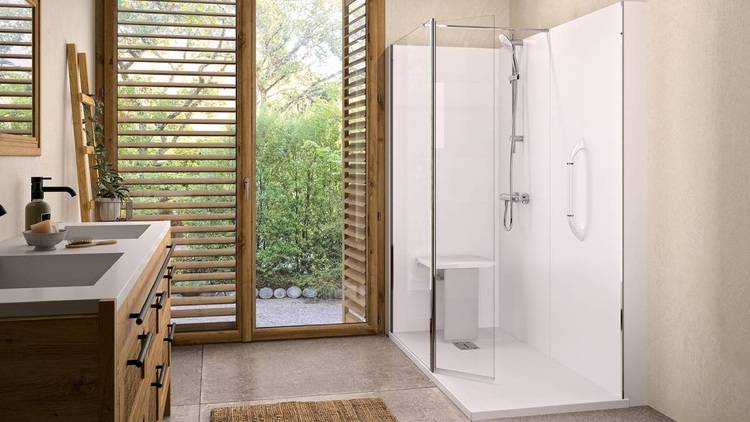 Ein modernes Badezimmer mit barrierearmer Ausstattung: eine bodengleiche Glasdusche, ein Waschtisch aus Holz mit unterfahrbarem Waschbecken, großes Fenster mit Jalousien für natürliche Belüftung und Energieeffizienz, Blick ins Grüne – ideal für nachhaltige Gebäudetechnikprojekte.