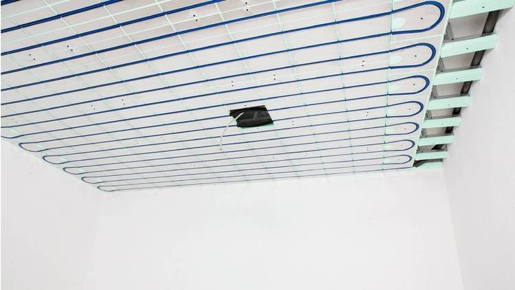 Alt-Text: „Installation eines effizienten Fußbodenheizungssystems mit sichtbaren blauen und grünen Rohrleitungen auf einer weißen Oberfläche, zur Optimierung der Energieeffizienz in modernen Gebäuden.“.