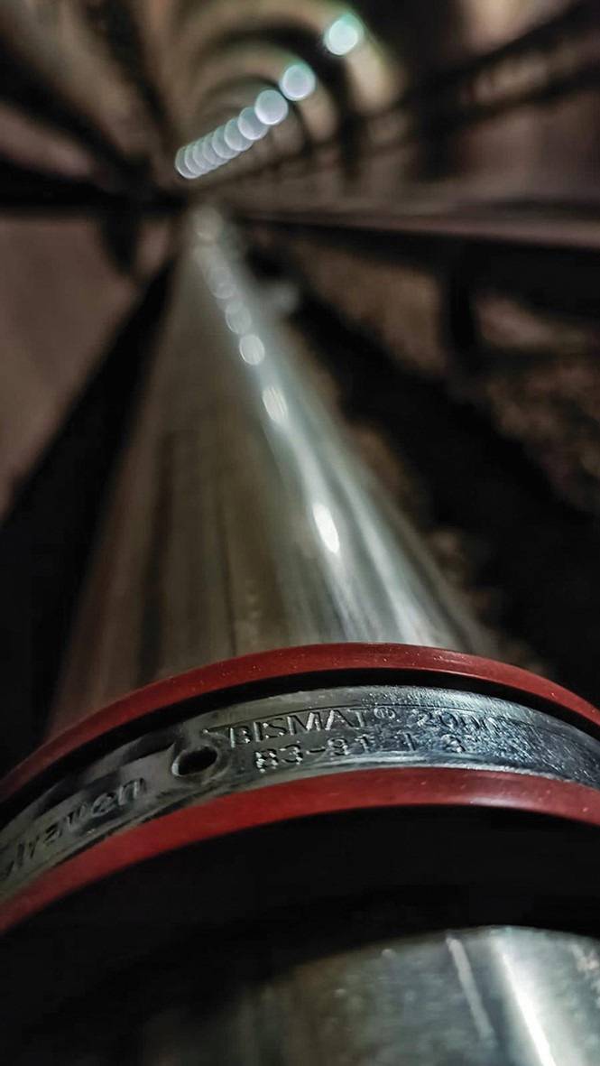 Alt-Text: „Nahaufnahme einer isolierten Metallrohrleitung mit farblicher Kennzeichnung für Heizungsinstallation in einem Wartungstunnel, symbolisiert Energieeffizienzlösungen in der Gebäudetechnik.