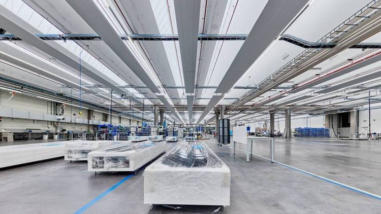 ALT-Text: „Geräumiges Industriegebäude mit stapelbaren Baumaterialien, hohen Decken und moderner Beleuchtung für effiziente Lagerhaltung in der Gebäudetechnikbranche.