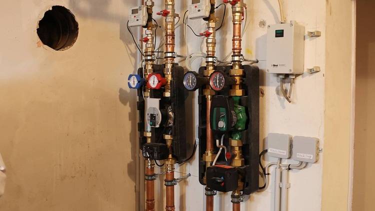 Alt-Text: „Rohrleitungssystem mit Ventilen und diversen Heizungssteuerungen in einem Technikraum, inklusive präziser Druckanzeiger und Kontrollboxen zur Überwachung der Heizungs- und Sanitärtechnik.“.