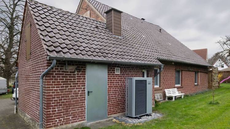 Effizientes Ziegelgebäude mit geneigtem Dach, ausgestattet mit moderner Außen-HLK-Anlage für optimierte Energieeffizienz in der Gebäudetechnik.