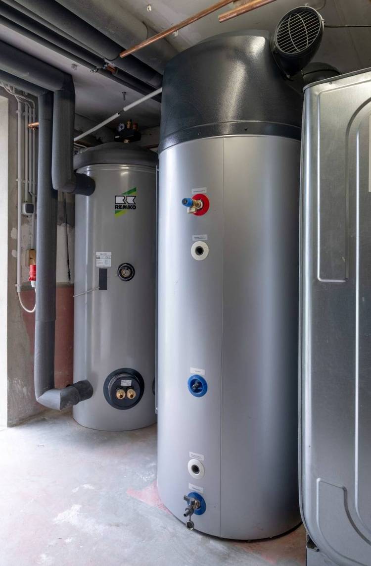 Alt-Text: „Zwei große industrielle Wassertanks mit angeschlossenen Rohrleitungen und Ventilen in einem Technikraum, dargestellt als zentraler Bestandteil eines effizienten Wassermanagementsystems für Gewerbegebäude.