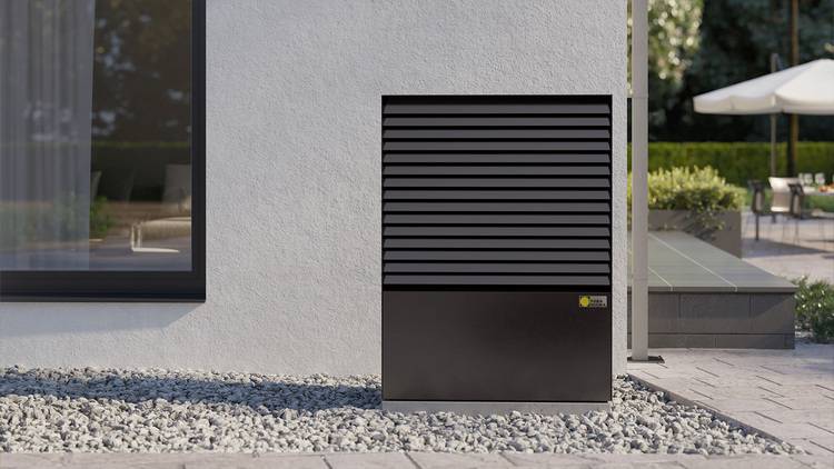 ALT-Text: „Moderne schwarze Außeneinheit einer Klimaanlage auf Kiesboden neben einem Gebäude, das für energieeffiziente Temperaturregelung gestaltet ist, mit Fokus auf Nachhaltigkeit und innovativer Gebäudetechnik.