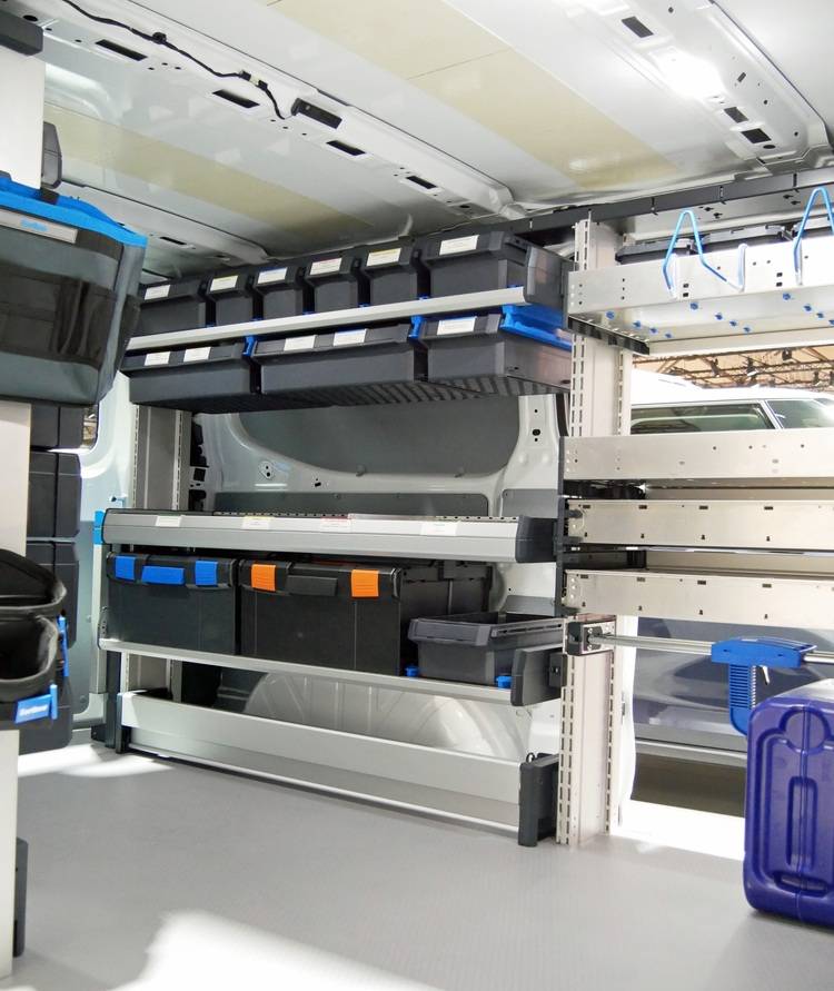 Alt-Text: „Innenansicht eines optimal eingerichteten Handwerkerfahrzeugs mit Regalsystem, blauen und schwarzen Aufbewahrungsboxen sowie speziellen Werkzeugen für Sanitär-, Heizungs- und Klimatechnik.