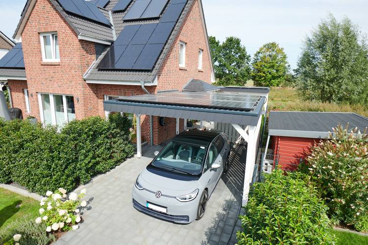 Alt-Text: „Effizienzhaus mit Photovoltaikanlage auf dem Dach, solarüberdachtem Carport und nachhaltig gestaltetem Garten als Beispiel für zukunftsorientierte Gebäudetechnik.