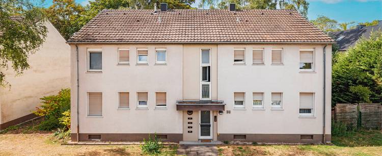 Zweistöckiges Gebäude in Beige mit Ziegeldach und Energiesparfenstern, Beispiel für energieeffiziente Bauweise in der Gebäudetechnik.
