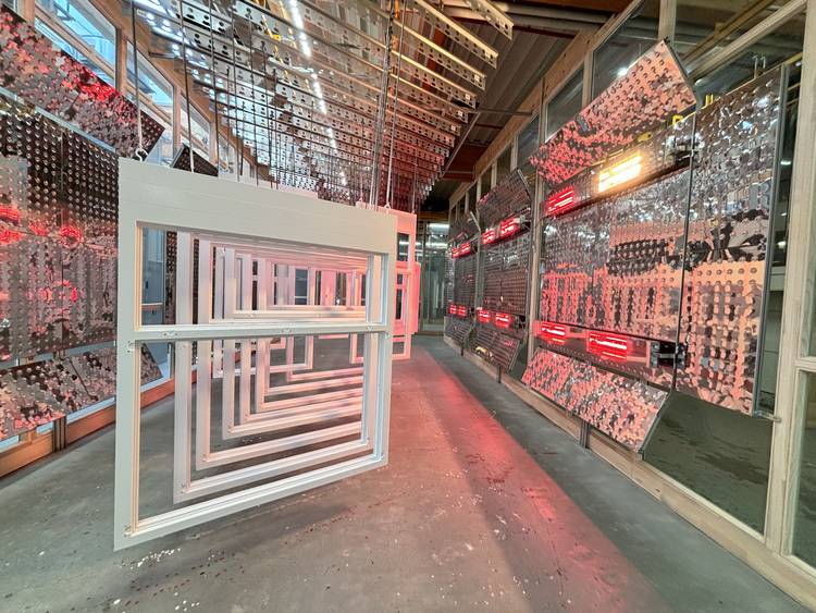 Moderne Installation in industrieller Umgebung mit Fokus auf Energieeffizienz: Gerahmte Strukturen und reflektierende Oberflächen werden durch rote Beleuchtung akzentuiert, symbolisieren innovative Gebäudetechnologien und nachhaltige Energielösungen.