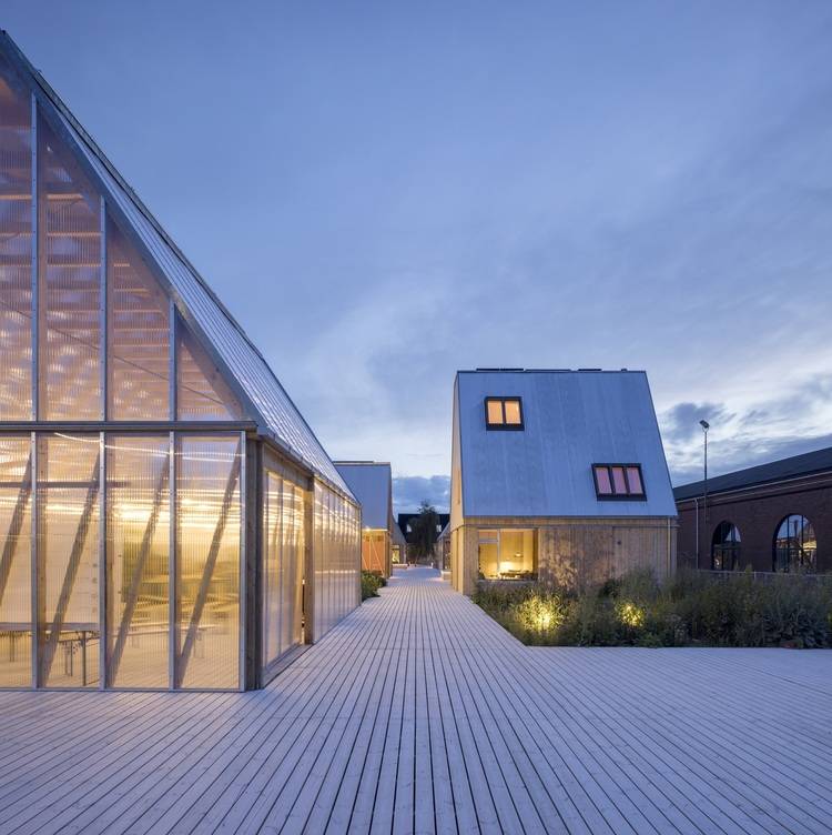 Alt-Text: „Moderne Gebäude mit Holzverkleidung und großen Glasfenstern, die innovative Energietechnologien integrieren und Energieeffizienz fördern; ideal für TGA-Planer und Architekten in der Gebäudetechnikbranche.