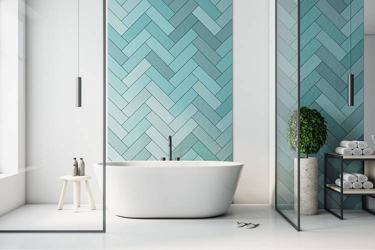 ALT-Text: Modernes Badezimmer mit frei stehender weißer Badewanne, türkisfarbenen Fischgrätfliesen als Akzentwand, einem grünen Pflanzenarrangement sowie Wandregalen zur Aufbewahrung von Handtüchern; Beispiel für effiziente Sanitärlösungen in der zeitgemäßen Gebäudetechnik.
