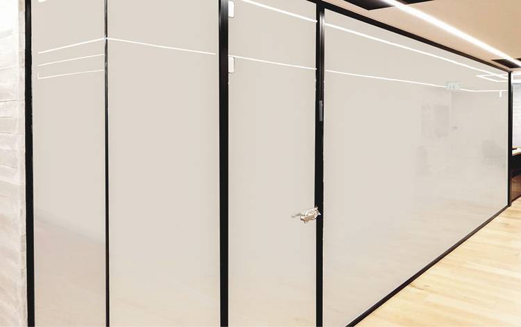 „Moderne Bürogebäude-Innenansicht mit großer Glaswand und schwarzem Rahmen, ideal für energieeffiziente Klimatisierung und innovative Beleuchtungskonzepte in der Gebäudetechnik.