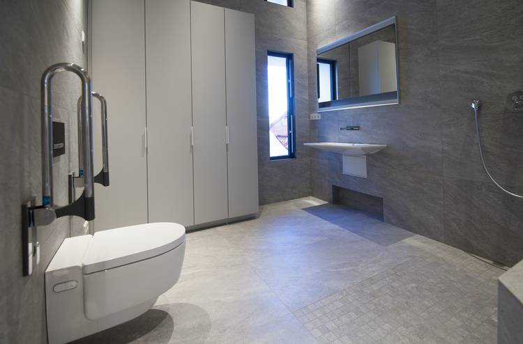 „Hochmodernes Badezimmer mit grauen Fliesen, wandhängender Toilette, Waschbecken und großem Spiegel für eine energieeffiziente Installation. Schmale Fenster für optimierten Lichteinfall in der Sanitärtechnik.