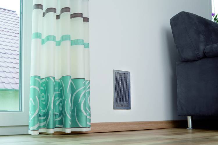 „Moderne Gebäudetechnik mit blauem Vorhang zur Verbesserung der Raumakustik, wandintegrierter Lüftung zur Optimierung der Klimatisierung und energieeffizient platziertem dunkelgrauen Sofa für zeitgemäße Innenraumgestaltung in gewerblichen Anwendungen.