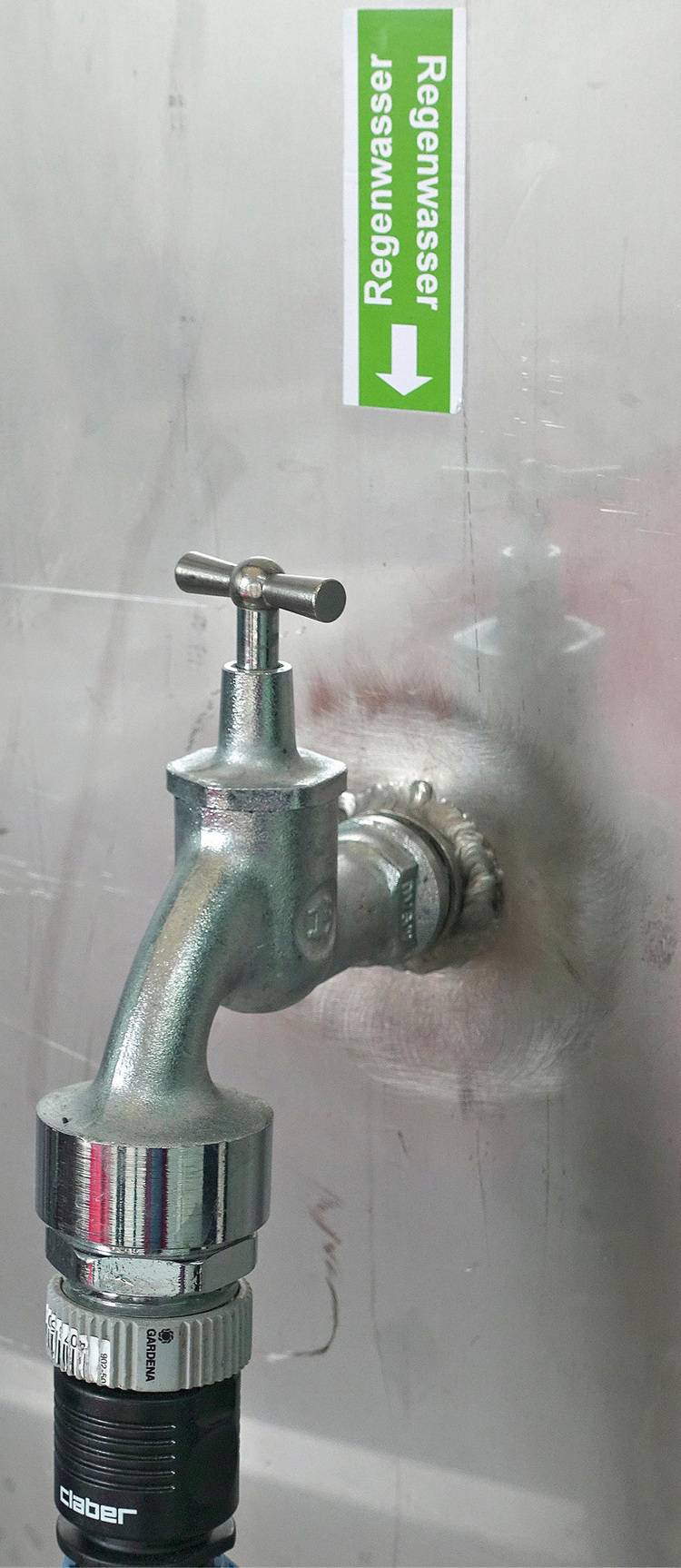 „Edelstahlarmatur mit Beschriftung ‚Regenwasser‘ in einer nachhaltigen Sanitärinstallation, die auf umweltfreundliche Wassernutzung in modernen Gebäuden abzielt.