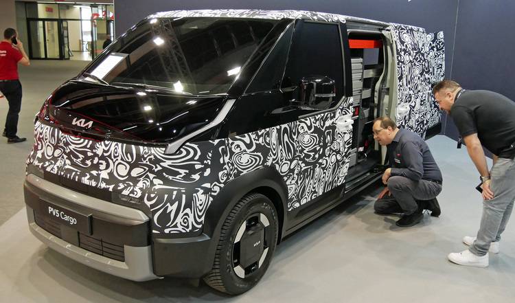 Sicher, hier ist ein optimierter ALT-Text für das beschriebene Bild: "Zwei Fachleute aus der Gebäudetechnik inspizieren einen getarnten Servicewagen mit geöffneter Schiebetür, der Innenausstattung für Werkzeuge und Materialien zur Installation von Sanitär-, Heizungs- und Klimatechnik zeigt.