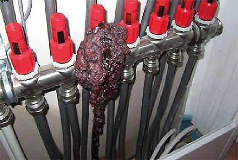 „Rohrsystem mit roten Endkappen, eine Leitung ist durch ein großes, dunkles faseriges Material blockiert, das auf eine mögliche Verstopfung in der Heizungs- oder Sanitärtechnik hinweist.“.