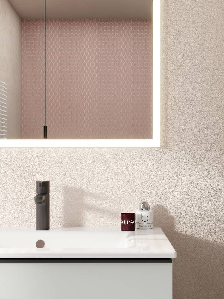 Modernes Badezimmer mit einem weißen Waschtisch, mattschwarzem Wasserhahn, hängender Leuchte und sechseckigen Wandfliesen – Beispiel für energieeffiziente Sanitärlösungen in der Gebäudetechnik.