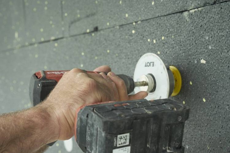 „Fachhandwerker befestigt mit Akkubohrschrauber einen weißen Dübel in der Wand, um eine stabile Grundlage für moderne Sanitärinstallationen zu schaffen.