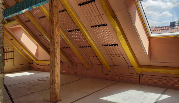 „Dachgeschoss im Bau mit sichtbaren Holzbalken zur Unterstützung der Struktur, hochwertiger Dämmung für optimale Energieeffizienz und einem Dachfenster für natürliche Belüftung in modernen Gebäudetechniklösungen.