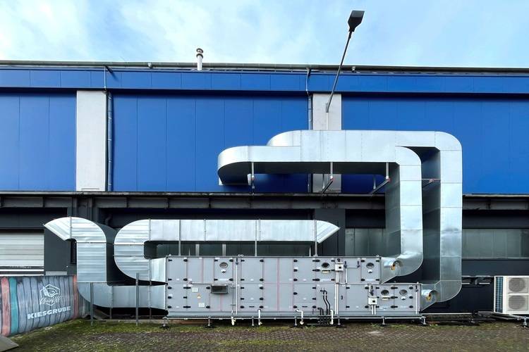 „Detailaufnahme eines industriellen Gebäudes mit großflächigem Netzwerk von Lüftungskanälen in Blau und Grau, die moderne HVAC-Technik für optimale Energieeffizienz und Klimaregulierung veranschaulichen.