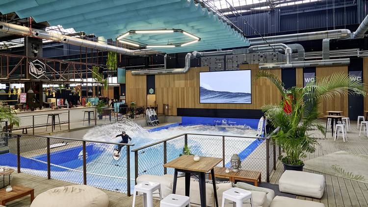 „Innovatives Indoor-Wellenbecken in einem modernen Gebäude mit nachhaltiger Heizungs- und Klimatechnik, umgeben von Schallschutzpanelen und energieeffizienter LED-Beleuchtung, geeignet für Wellnessanbieter und Freizeitparkbetreiber.“.