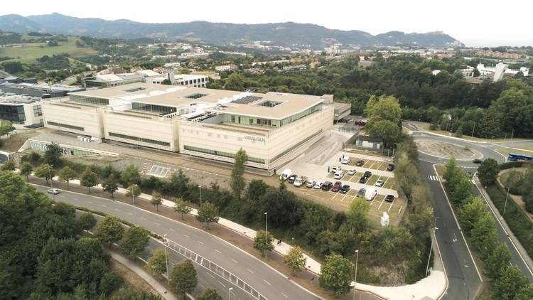 Optimierter ALT-Text für die Zielgruppe und das Themenfeld: „Luftaufnahme eines energieeffizienten, modernen Bürogebäudes mit Flachdach, Photovoltaikanlagen und großzügigen Parkflächen; das Gebäude ist von Grünanlagen umgeben und zeigt bauliche Lösungen der aktuellen Gebäudetechnik.“.