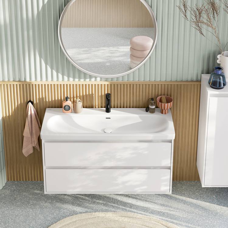 „Modernes Badezimmer mit runder LED-Spiegelleuchte, weißem Waschtisch aus umweltfreundlichem Material, mattschwarzer Einhebelmischer-Armatur und dekorativen Elementen auf einer Wandverkleidung aus nachhaltig produziertem Holz. Ideale Lösung für energieeffiziente Gebäudetechnik.