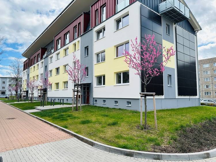 Gerne! Hier ist ein optimierter, auf die Zielgruppe und den Kontext zugeschnittener Alt-Text: „Mehrgeschossiges Wohngebäude mit moderner Fassadentechnik, umgeben von begrünten Außenanlagen; Beispiel für energieeffiziente Gebäudehülle und nachhaltige Stadtentwicklung.“ Falls der Fokus auf technische Details wie Heizungs-, Lüftungs- oder Energiekonzepte liegen soll, kann dies entsprechend präzisiert werden.