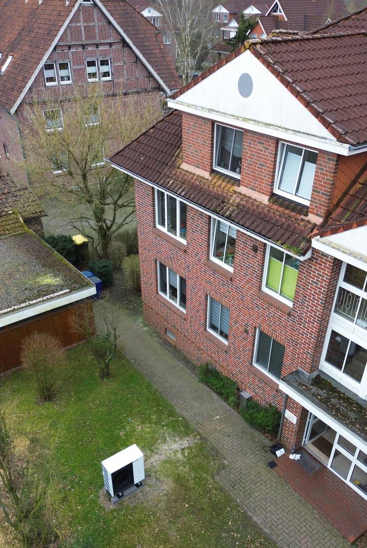 Gerne, hier ist ein optimierter ALT-Text für das beschriebene Bild im Kontext von haustec.de und der genannten Zielgruppe: „Luftbild eines Mehrfamilienhauses aus Klinker mit gepflegtem Außenbereich und sichtbar installierter Außeneinheit einer Split-Klimaanlage zur energieeffizienten Kühlung.“ Falls gewünscht, kann der Text je nach Themenschwerpunkt (z. B. Energieeffizienz, Klimatechnik) weiter angepasst werden.