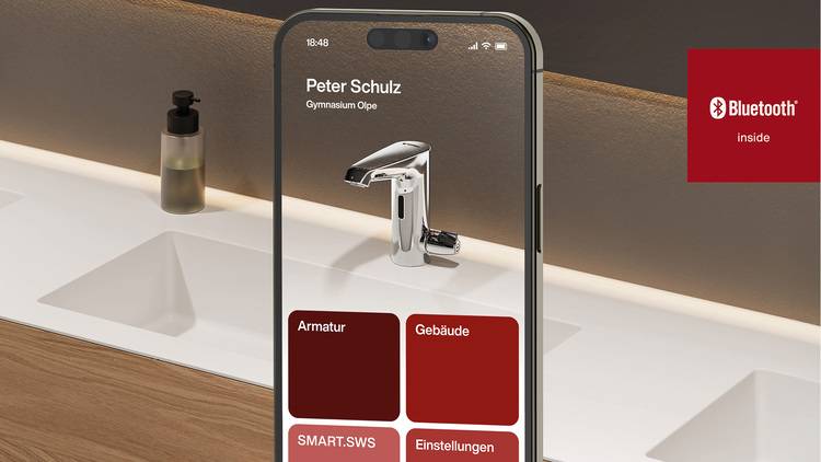 Optimierter ALT-Text: „Moderne Armatur in einem Badezimmer wird per Smartphone-App über Bluetooth gesteuert; die digitale Bedienung und das Bluetooth-Symbol unterstreichen den Trend zur smarten Gebäudetechnik im SHK-Bereich.“.