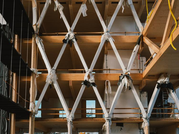 Optimierter ALT-Text: „Rohbau eines modernen Gebäudes mit sichtbaren Holztragwerken, Zwischendecken und provisorischen Ländern – Fokus auf nachhaltige Bauweise und innovative Gebäudetechnik für Energieeffizienz.“.